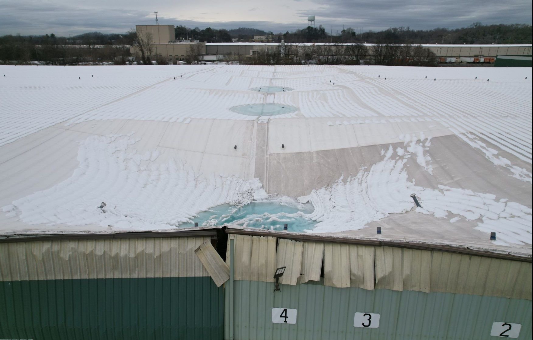 Aerial view of snow load damage and structural collapse on an industrial TPO roof in Knoxville, TN